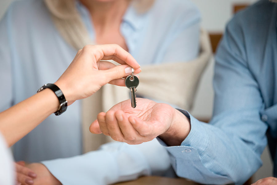 Entrega de llaves a una pareja por parte de un agente inmobiliario